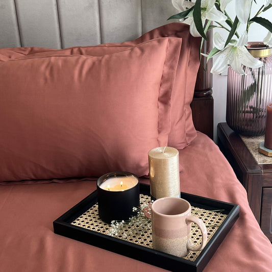 Terracotta bedsheet styled on a made bed