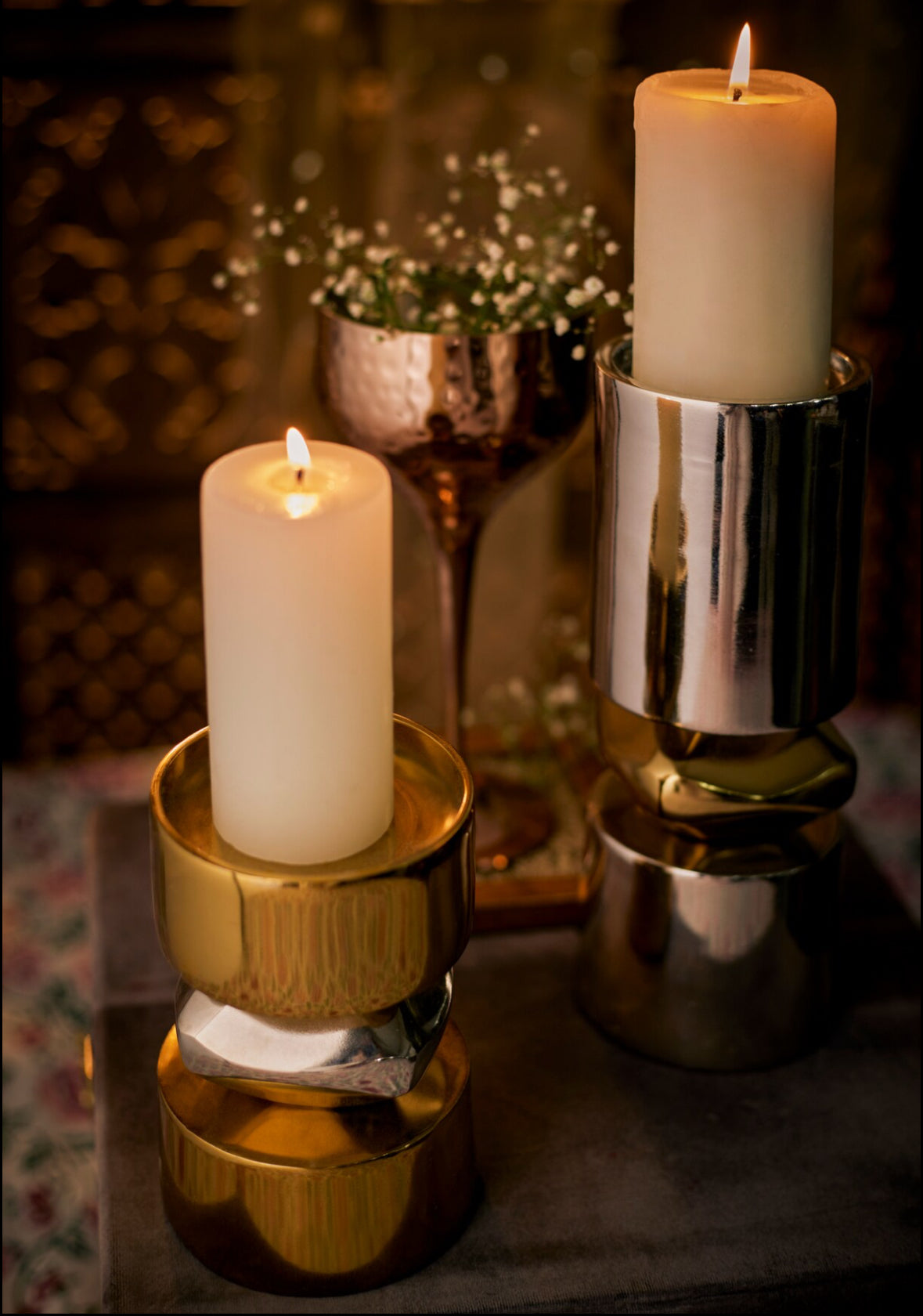 Elegant gold and nickel candle stands with lit candles creating a cozy ambiance.