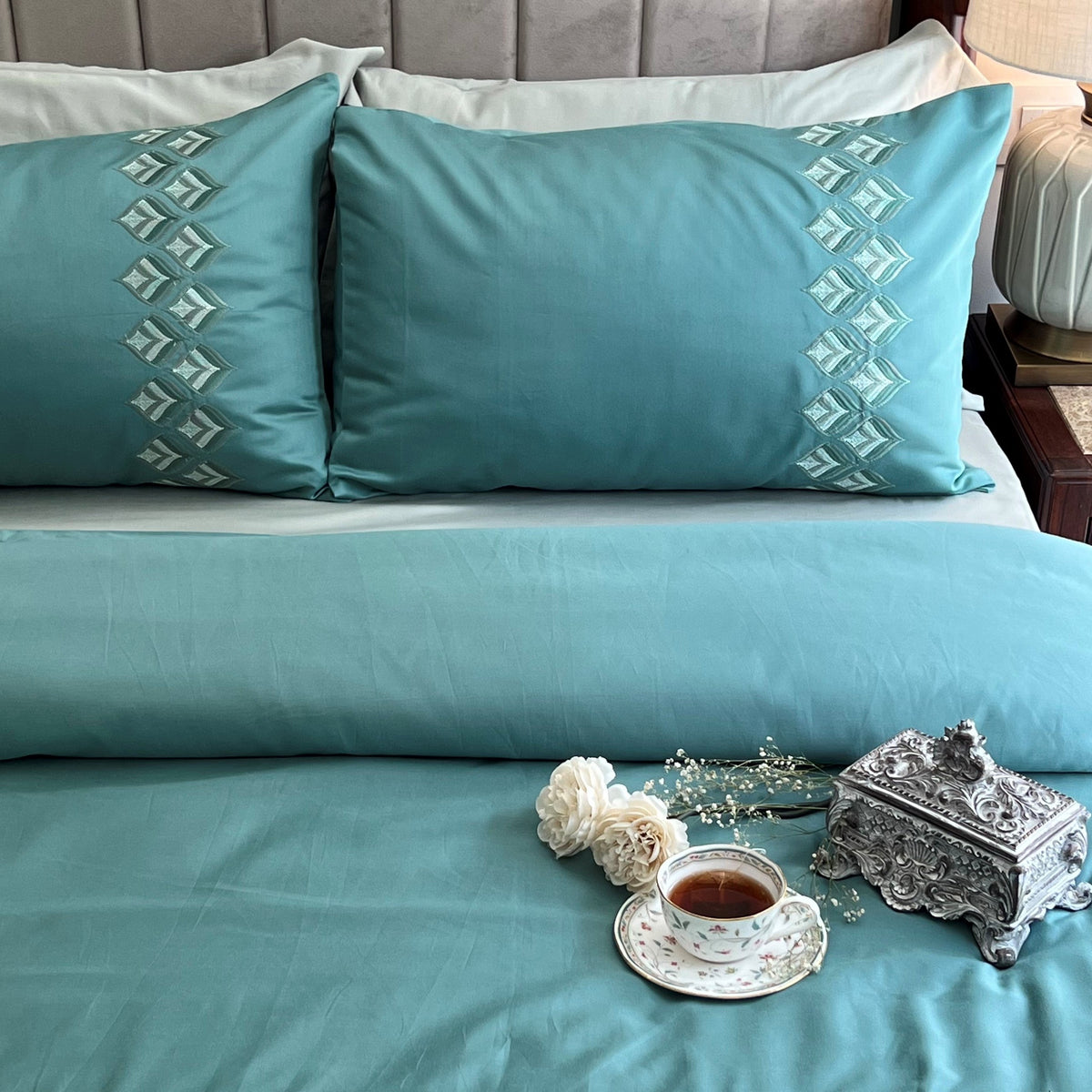 Close-up of turquoise embroidered leaflet pattern pillow cover