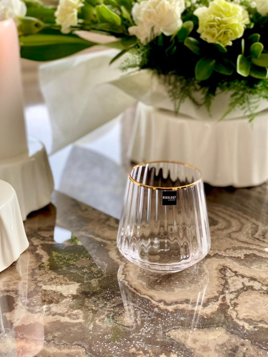Close-up of gold rimmed whiskey glass on marble table.