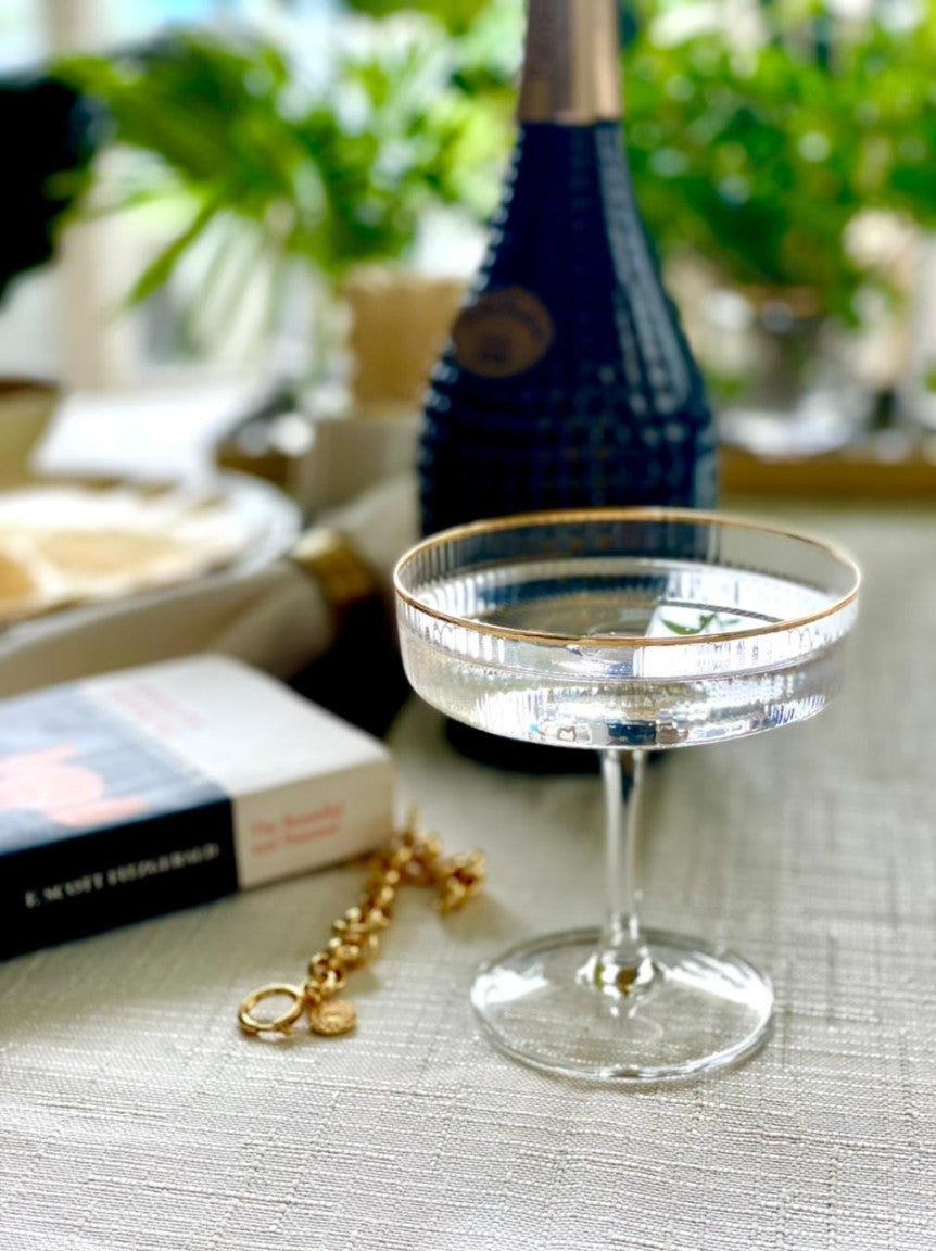 Elegant coupe glass with gold rim detail on set table.