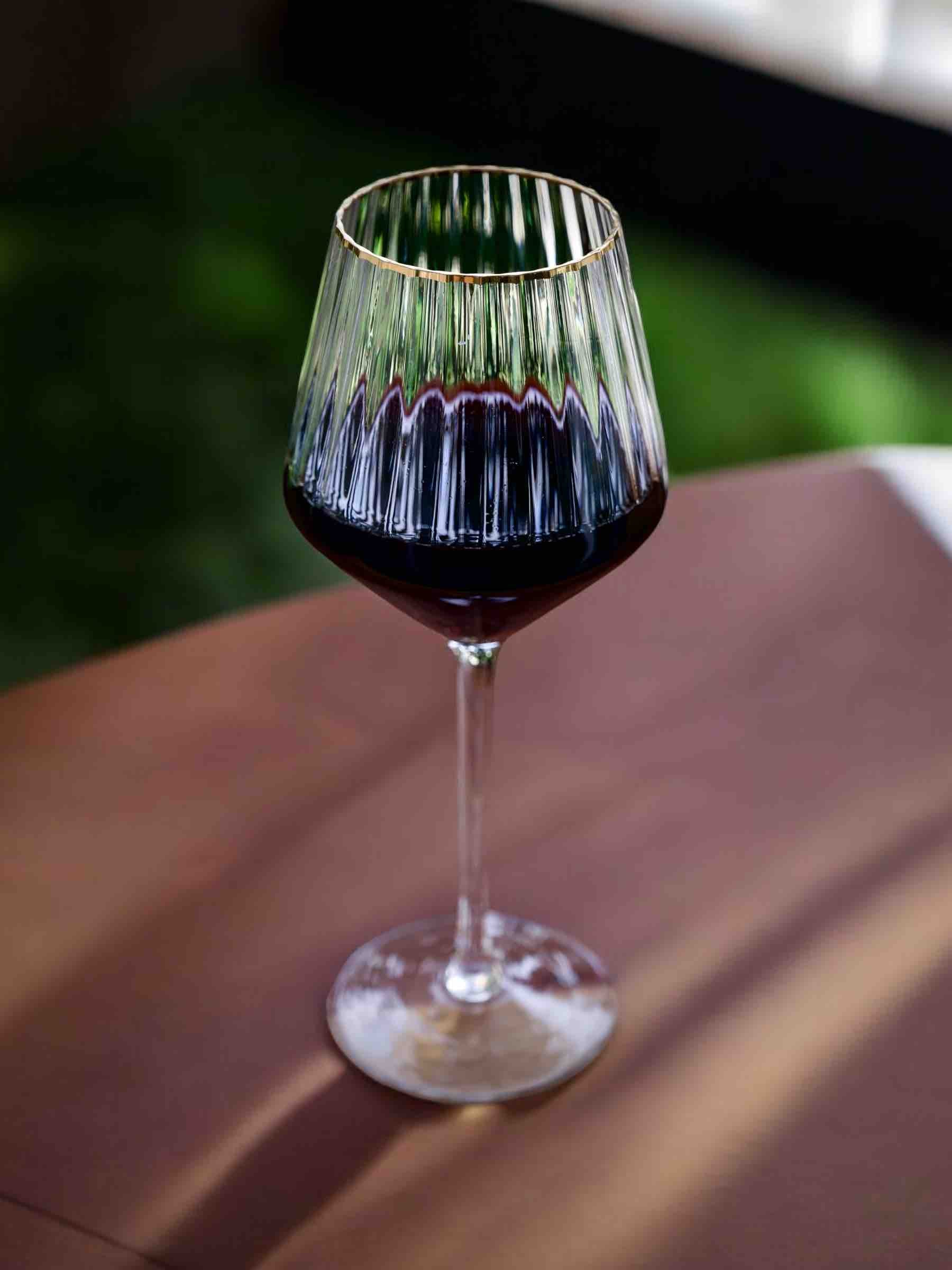 Elegant red wine glass with a gold rim detail.