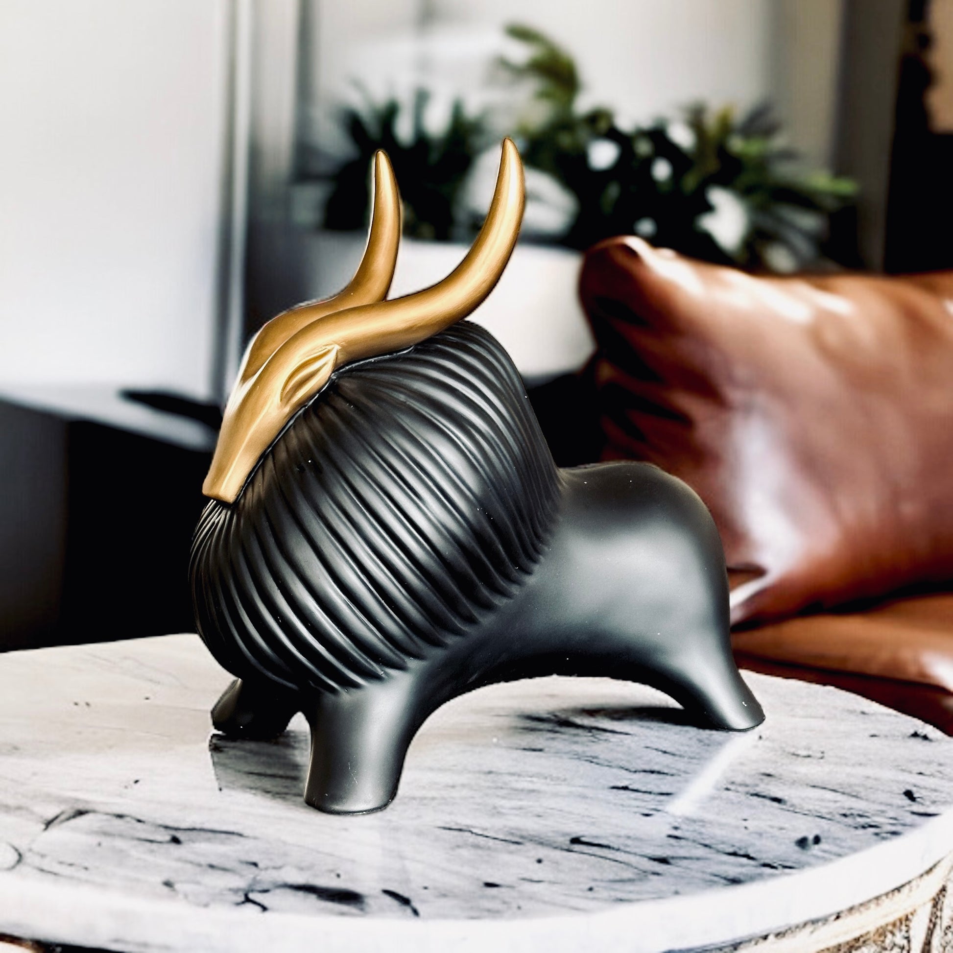 Black yak decor with gold horns on a marble table.