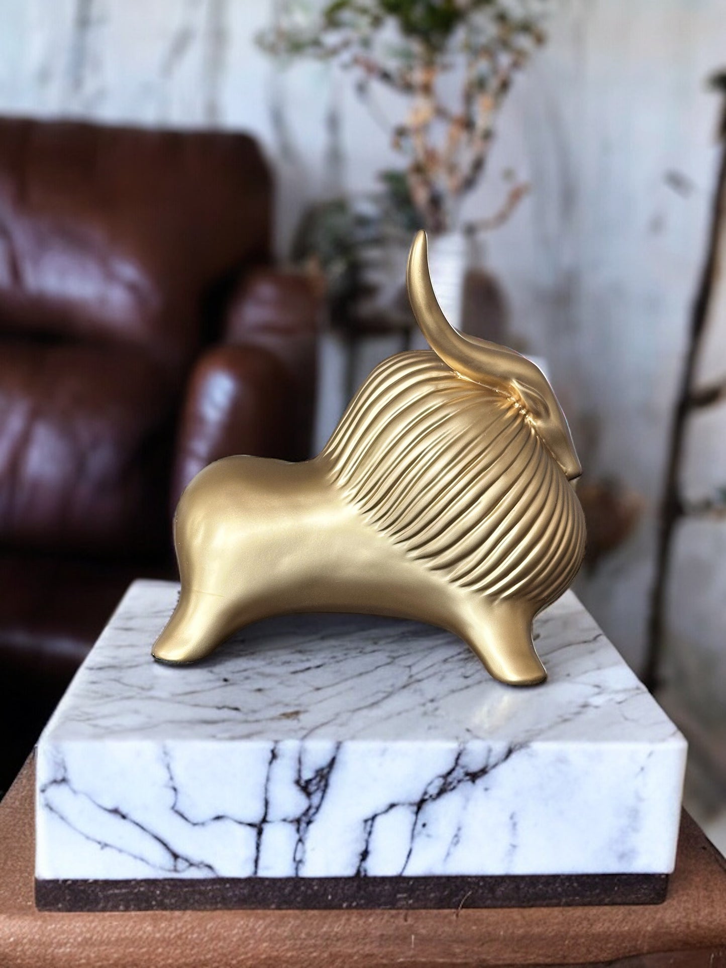 Gold yak decor with detailed texture on a marble stand.