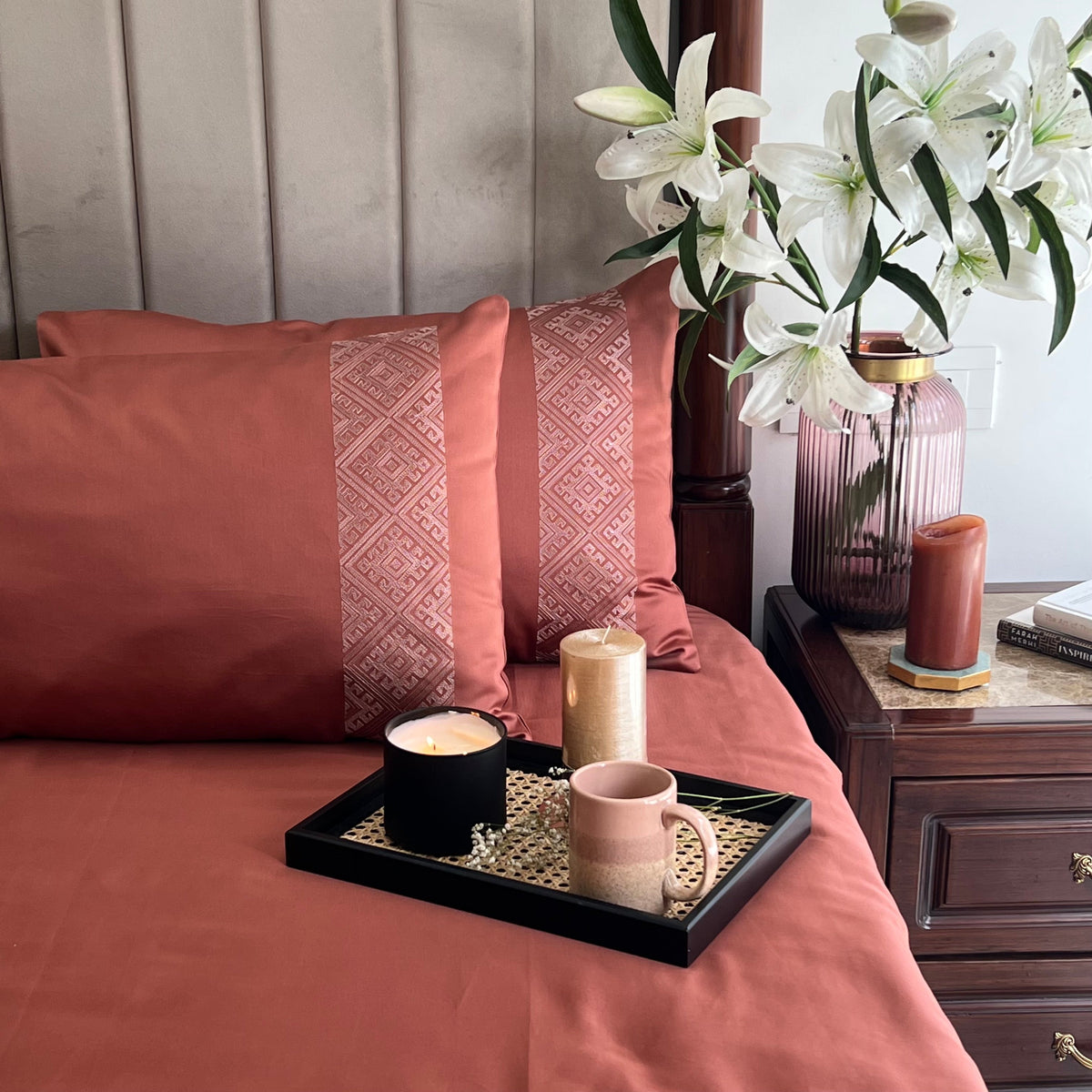 Flat lay of terracotta bedsheet and embroidered pillow covers