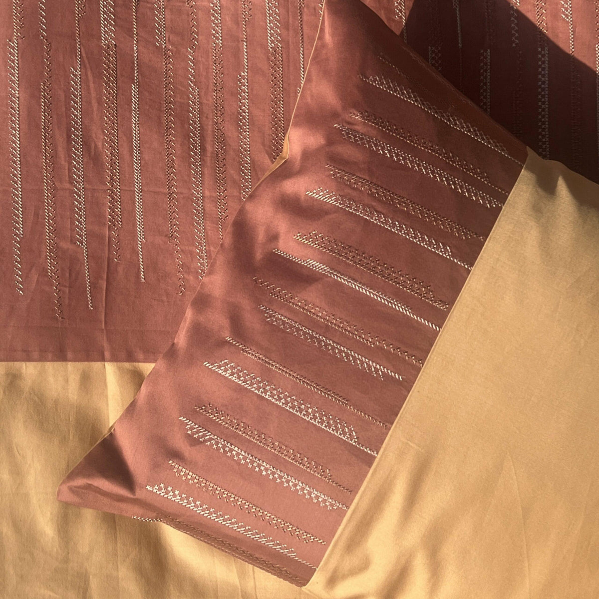 Close-up of embroidered pillow cover in terracotta and honey mustard
