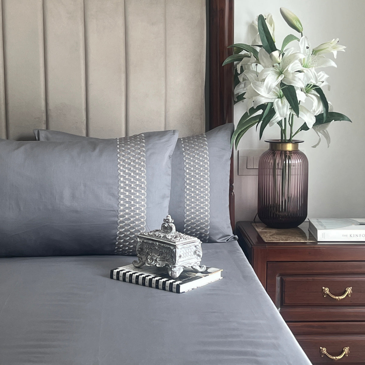 Dark grey bedsheet set with embroidered pillow covers styled on bed