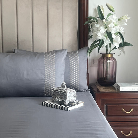 Dark grey bedsheet set with embroidered pillow covers styled on bed