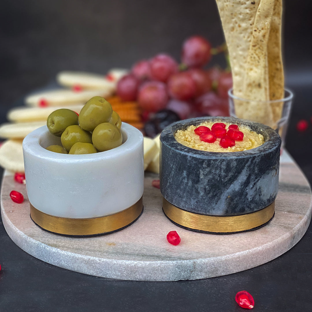 Elegant marble condiment bowls with brass detail, perfect for serving.