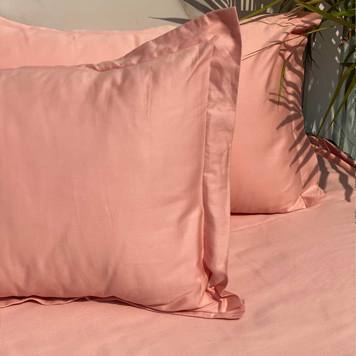 Coral bedsheet and pillow covers styled on a made bed