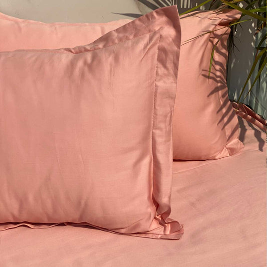 Coral bedsheet and pillow covers styled on a made bed