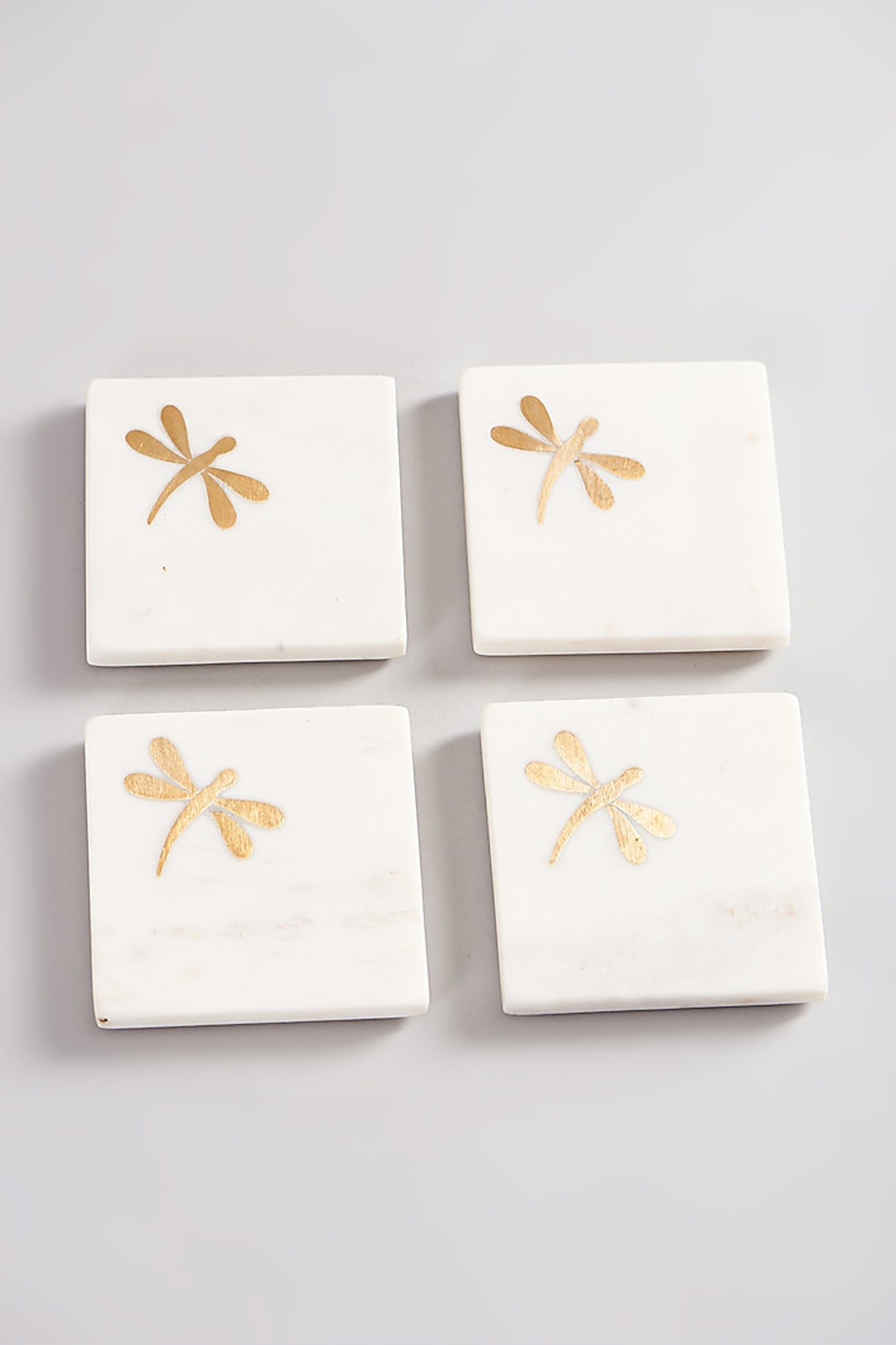 Set of marble coasters with brass dragonfly accents.